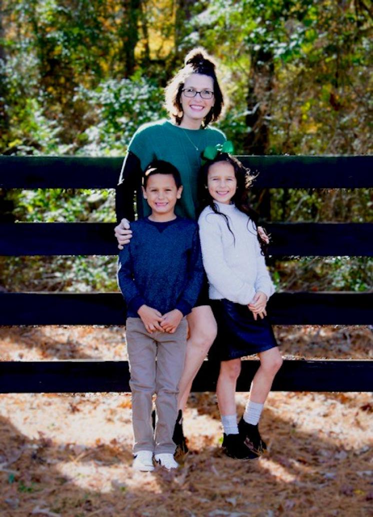 A mother posing with her 2 children outside