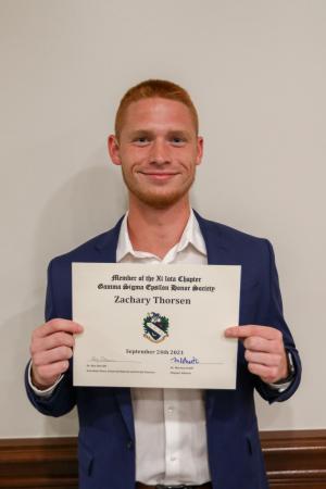 Person holding a certificate while standing against a wall.