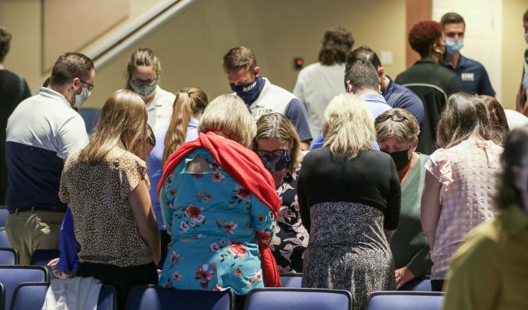 A group of people gathered in a room with blue seats.