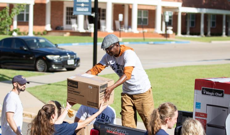 People unloading boxes from a truck in a residential area.