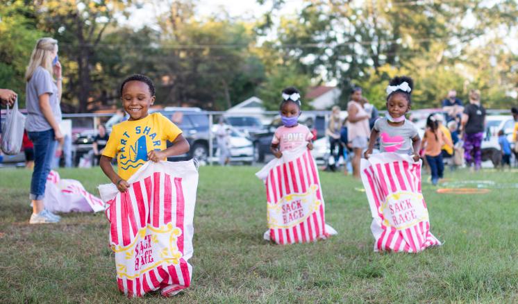 Children participating in a sack race outdoors.