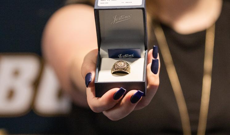 A person holding an open box with a ring inside.