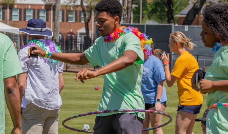Man hoola hooping outside with other people around him