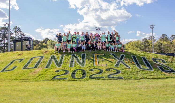 Group picture of students behind of the Connexus words written in the ground