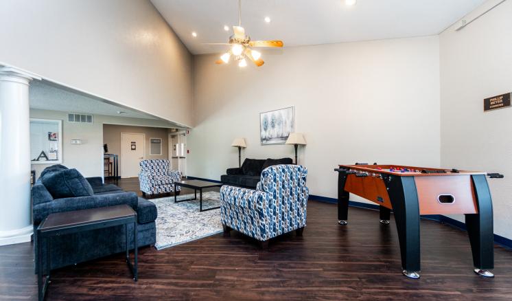 Spacious living room with dark wood floors, modern furniture, and a foosball table.