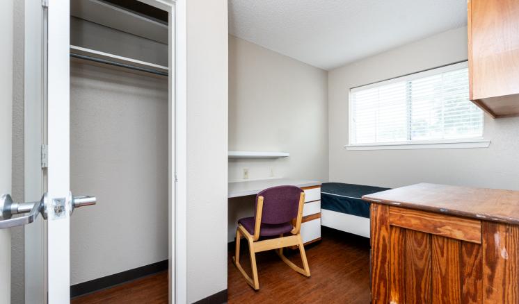 Small room with a closet, desk, chair, twin bed, and window.