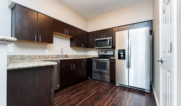 Modern kitchen with dark wood cabinets, stainless steel appliances, and granite countertops.