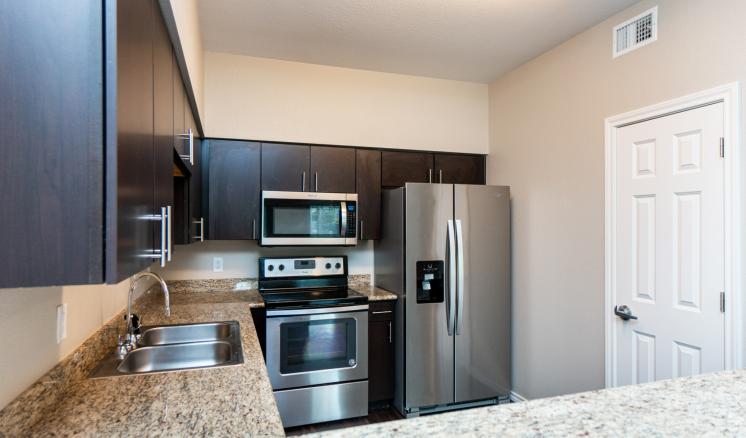 Modern kitchen with stainless steel appliances and dark cabinets.