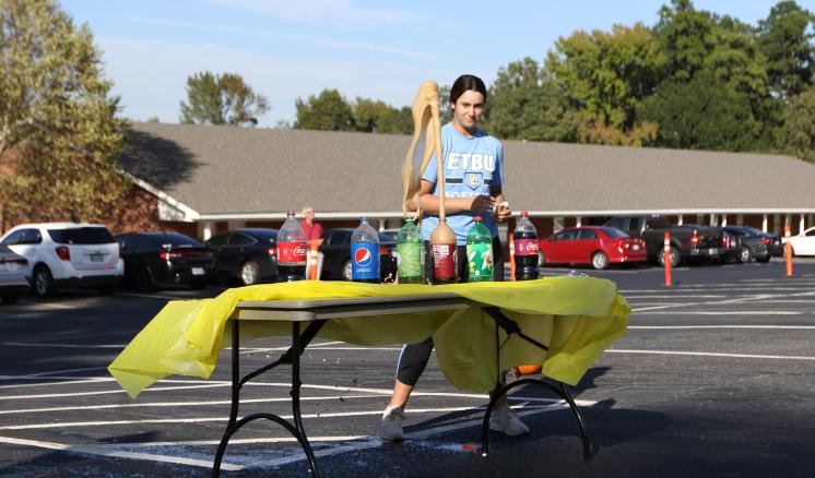 a woman standing behind a table with a yellow tablecloth