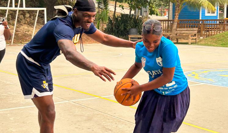 ETBU Men's Basketball player plays a game of basketball with a student in Honduras