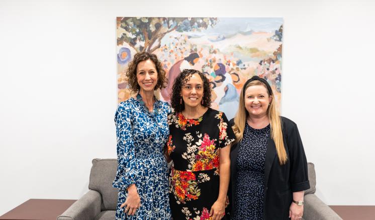 3 women stood inside in floral pattern clothing smiling next to each other in a group
