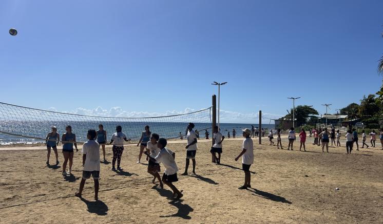 A group of people playing volleyball on the beach together