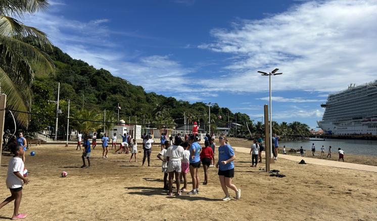 A group of people playing volleyball on the beach together