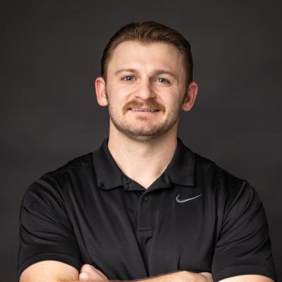 A man in a black nike shirt standing in front of a dark backdrop